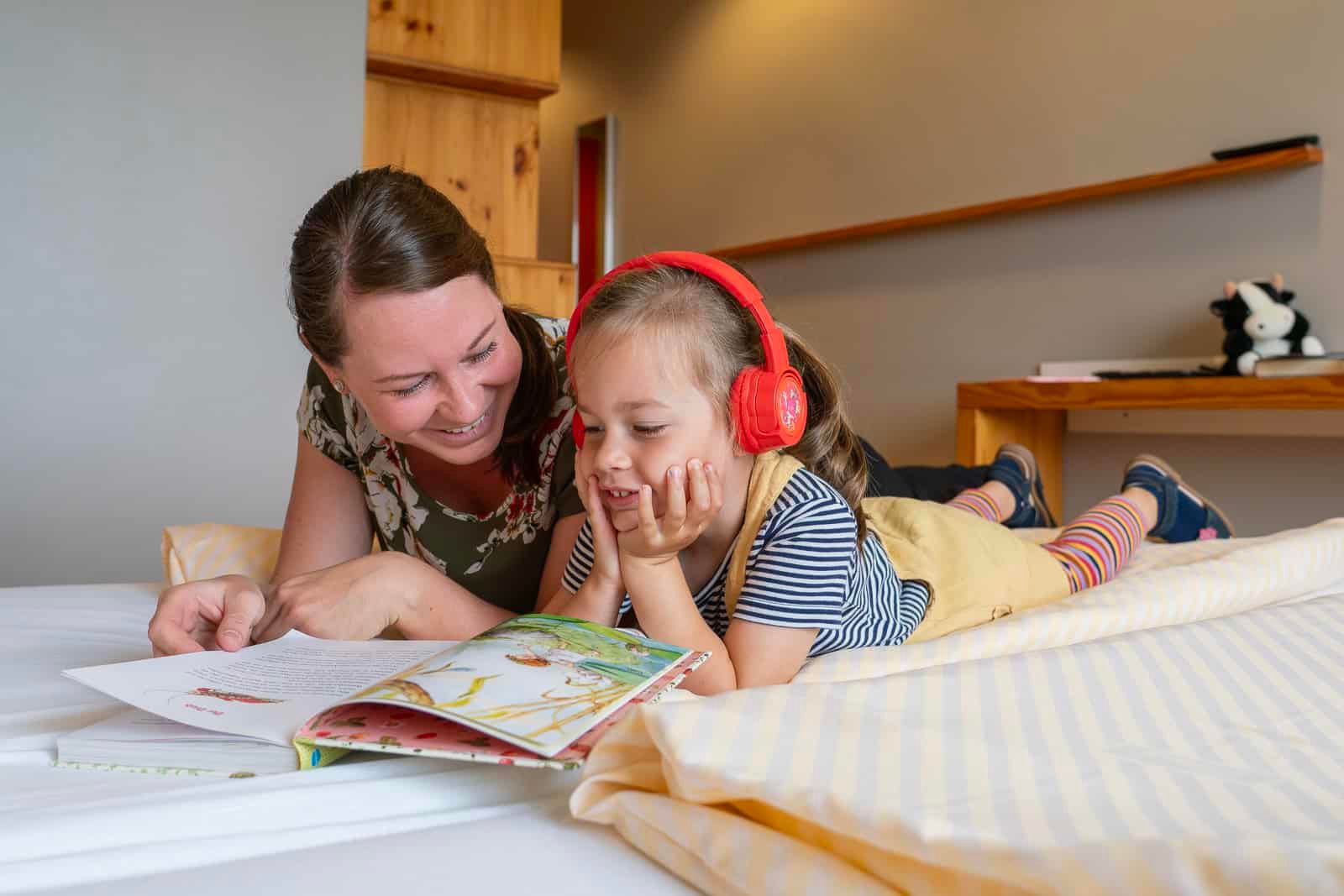 Mutter und Kind entspannen im Zimmer des Hotel Haus 54 in Zingst und lesen gemeinsam ein Buch