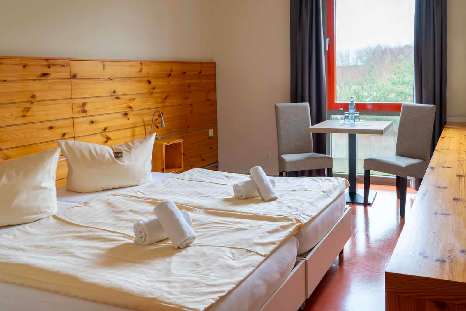 Helles, modern eingerichtetes Doppelzimmer im Hotel Haus 54 in Zingst mit Tisch, Stühlen und Blick ins Grüne