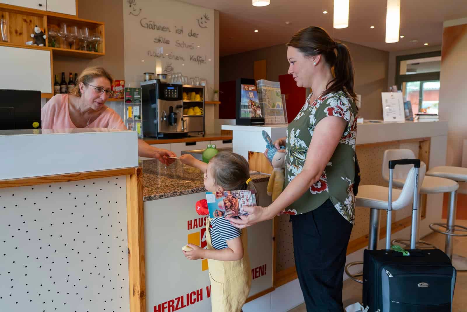 Familie beim Check-in an der Rezeption im Hotel Haus 54 in Zingst