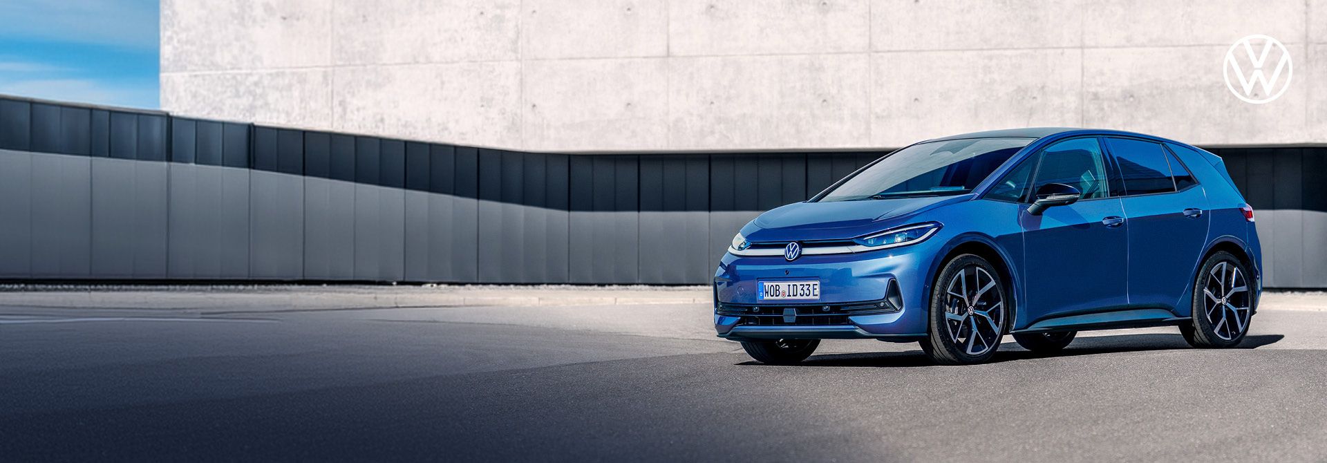 Volkswagen ID.3 Neo in blau steht auf der Straße vor einem minimalistischen Indutriegebäude