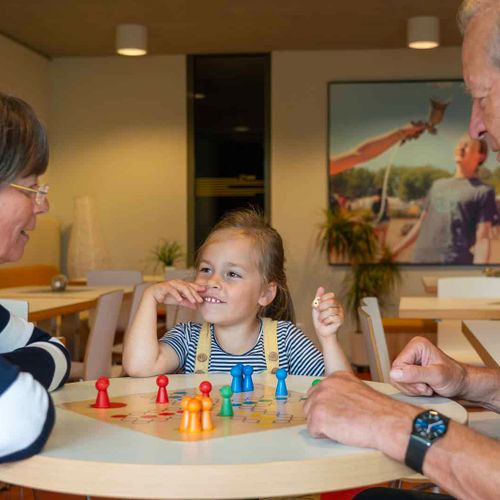 Familie spielt gemeinsam ein Brettspiel in der Lounge des Hotel Haus 54 in Zingst