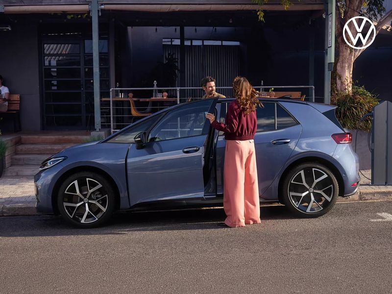 Volkwagen ID.3 Neo mit einem Pärchen vor einem Cafe