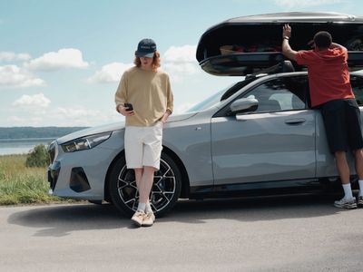 BMW 5er Touring mit Dachgepäckträger un dzwei Personen am Auto stehend auf einer Landstrecke