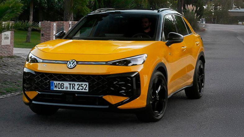 Frontansicht eines Volkswagen T-Roc Life in moderner SUV-Optik mit markantem Kühlergrill, schmalen LED-Scheinwerfern und erhöhtem Fahrwerk, aufgenommen bei Tageslicht auf einer Straße.