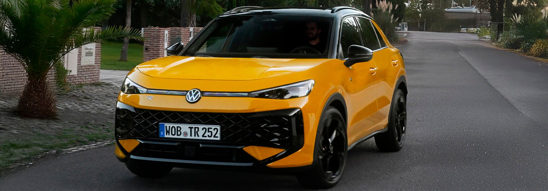 Frontansicht eines Volkswagen T-Roc Life in moderner SUV-Optik mit markantem Kühlergrill, schmalen LED-Scheinwerfern und erhöhtem Fahrwerk, aufgenommen bei Tageslicht auf einer Straße.